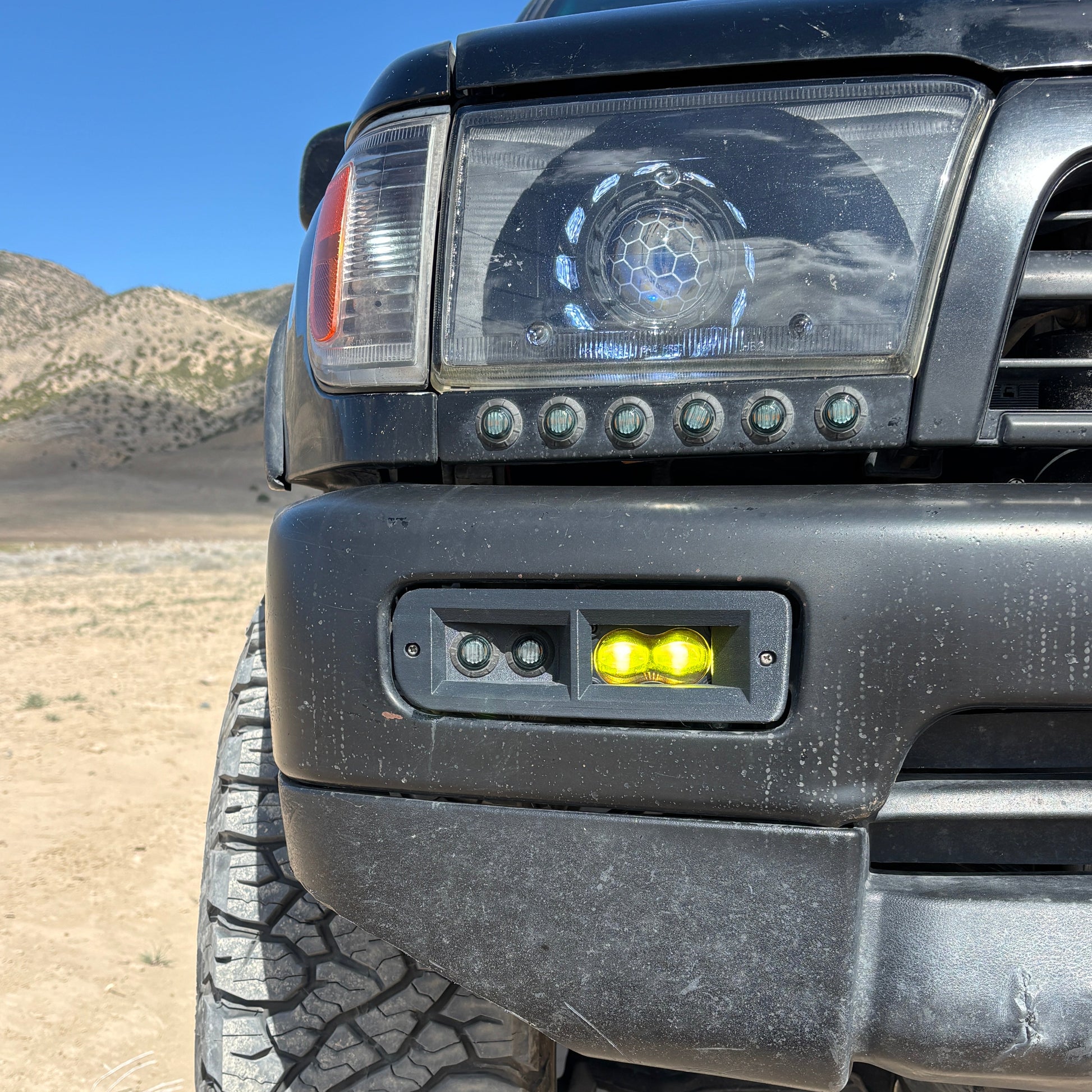 Close-up of a vehicle's front bumper with lights in a desert setting