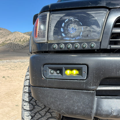 Close-up of a vehicle's front bumper with lights in a desert setting